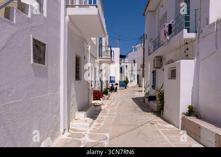 Parikia, Paros, GR - 22 août 2025 : une rue dans la vieille ville de Parikia avec des maisons blanches et des détails peints en bleu Banque D'Images