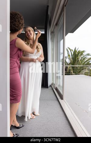 Divers amis féminins appliquant le pinceau de maquillage à la mariée dans la robe, copier l'espace Banque D'Images