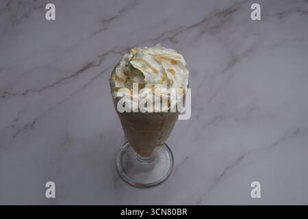 Dégustez un délicieux café flotté au caramel garni de crème fouettée pour un régal ultime Banque D'Images
