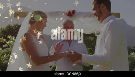 Échange d'anneaux de mariage mariée et mariée debout à l'extérieur sous arche en bois, avec un décor floral Banque D'Images