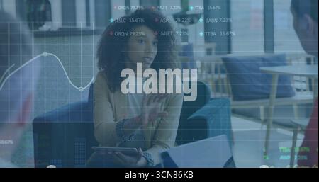Expliquant femme d'affaires gestuelle avec tablette dans le salon de bureau, graphiques de stock financier flottant Banque D'Images
