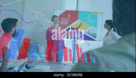 Pointant femme d'ascendance diverse présentant des données dans la salle de conférence avec infographies et ordinateurs portables Banque D'Images