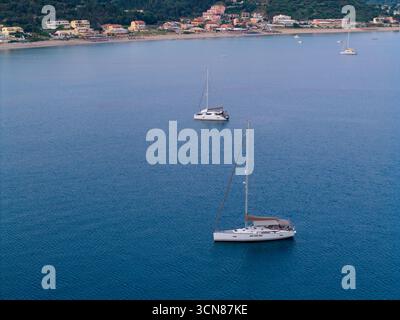 Voiliers ancrés dans la baie tranquille d'Agios Georgios Pagon, Corfou, au crépuscule. Vue aérienne d'un beau village de villégiature grec, représentant un pe Banque D'Images
