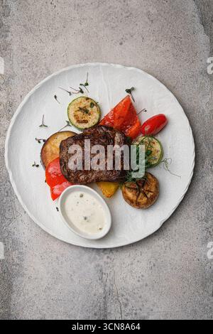 Délicieux steak grillé accompagné d'une variété de légumes frais assortis et de sauces trempées Banque D'Images