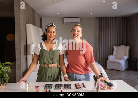 Diverses amies féminines arrangeant des pinceaux de maquillage, des palettes sur le comptoir de la chambre avec des plantes en pot Banque D'Images