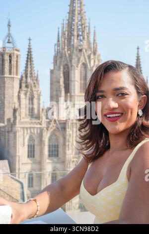 Une femme sourit et porte une robe jaune assise sur un balcon donnant sur une grande cathédrale. Concept de bonheur et de détente, comme le WO Banque D'Images