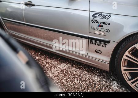 Milan, italie 20 septembre 2025 : panneau latéral de voiture de sport bmw avec autocollants et logos de sponsor sur la carrosserie argentée, garé sur du gravier, montrant les détails de réglage Banque D'Images