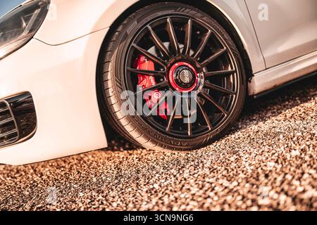 Milan, italie 20 septembre 2025 : voiture de sport blanche debout sur du gravier montrant une jante noire personnalisée, un pneu à profil bas et un étrier de frein rouge haute performance Banque D'Images