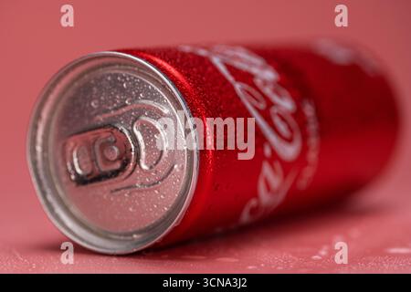 Une canette de Coca-Cola est assise sur une table. La boîte est rouge et a un dessus argenté. Le bidon est ouvert et présente de la condensation Banque D'Images