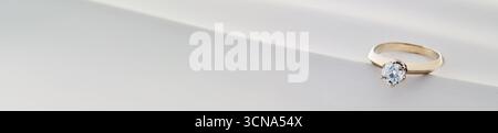 Une bague en or avec un diamant est sur un fond blanc. La bague est le centre principal de l'image, et c'est un symbole d'amour et d'engagement. Le bac blanc Banque D'Images