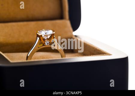 Une bague en or et diamant est dans une boîte. La boîte est noire et l'anneau brille Banque D'Images