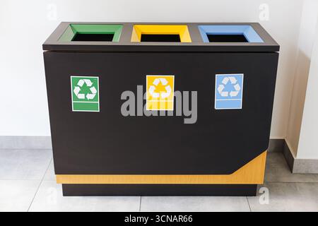 Bacs de recyclage à l'intérieur. Trois conteneurs colorés avec éco-signes. Système de séparation de déchets dans un bâtiment public. Protection de l'environnement. Banque D'Images