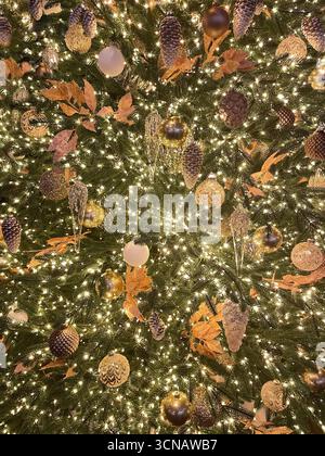 Arbre de Noël brillant de luxe avec boules métalliques dorées et transparentes, pommes de pin, feuilles et guirlande lumineuse. Motif de vacances de Noël. Tendance et créati Banque D'Images