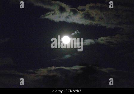 Scène nocturne mesmorisante d'une pleine Lune entourée de nuages Banque D'Images