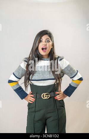 Une jeune femme debout avec une expression choquée et surprise sur son visage. Femme surprise avec les mains sur les hanches - Studio Portrait Banque D'Images
