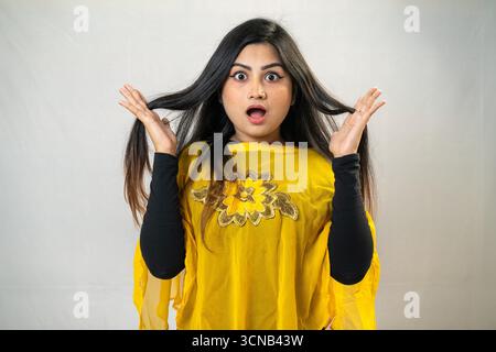 Une jeune femme avec une expression choquée, tenant ses cheveux vers le haut. Femme surprise avec Top jaune - Studio Portrait Banque D'Images