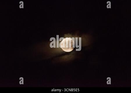 Scène nocturne fascinante d'une pleine Lune jetant un œil à travers un nuage épais Banque D'Images