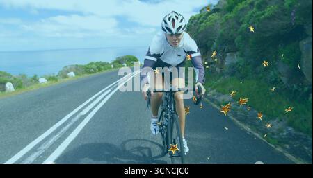 Cycliste sur vélo de route portant un casque le long de la route côtière avec des étincelles en forme d'étoile dorée Banque D'Images