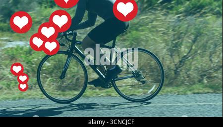 Cycliste masculin portant maillot et short sur vélo le long de la route rurale pavée, montrant des icônes de coeur Banque D'Images