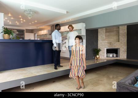 Agent immobilier guidant les clients à travers la maison avec îlot de cuisine, tablette Banque D'Images