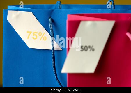 Deux sacs à provisions avec 75% et 50% écrit dessus. Les sacs sont bleus et roses. Soldes Banque D'Images