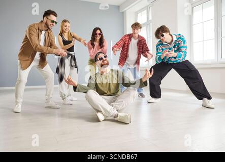 Cool danseur homme, groupe de personnes dansant activement dansant à l'intérieur, se déplaçant et posant dans l'espace studio Banque D'Images