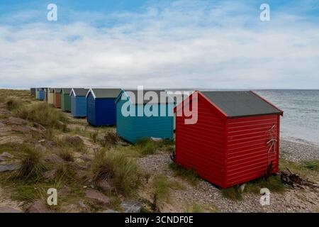 Des cabanes de plage colorées bordent l'étendue de la plage de Findhorn, offrant une vue pittoresque sur le Moray Firth. Banque D'Images