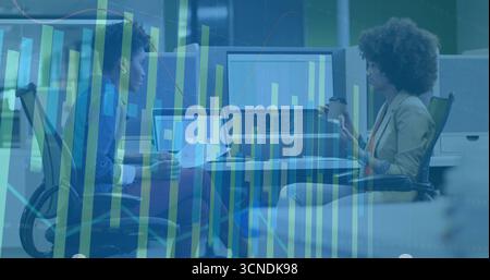 Collaboration de collègues analysant des graphiques de données au bureau, avec des ordinateurs portables, un moniteur et une tasse à café Banque D'Images