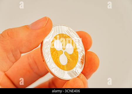 Image en gros plan d'une pièce de monnaie Tether tenue par une main anonyme, à l'intérieur de la pièce Ripple A. Banque D'Images