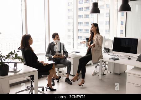 Femme professionnelle positive présentant un plan de travail d'équipe à ses collègues Banque D'Images