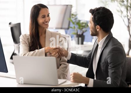 Heureuse femme d'affaires néo-zélandaise serrant la main à l'homme partenaire Banque D'Images