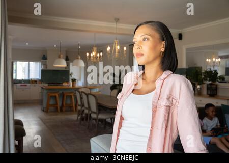 Mère avec garçon afro-américain debout dans le salon près de la table à manger en bois, espace de copie Banque D'Images