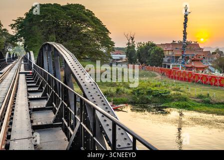 Le soleil se couche derrière une statue de temple bouddhiste, vers des montagnes lointaines, lumière chaude dorée reflétant de l'eau de la rivière, à l'attrac touristique populaire Banque D'Images