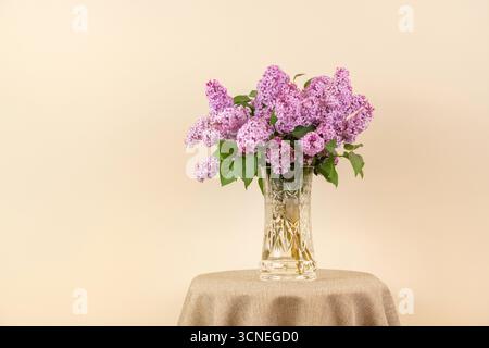 Un vase de fleurs violettes se trouve sur une table. Les fleurs sont dans un vase clair et sont disposées de manière à ce qu'elles ressemblent à un bouquet. T Banque D'Images