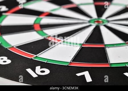 Gros plan d'un jeu de fléchettes noir et blanc avec les chiffres 16 et 7 dessus. La planche est entourée d'une bordure verte Banque D'Images