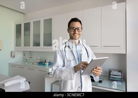 Portrait heureux amical médecin masculin regardant la tablette de support de caméra Banque D'Images