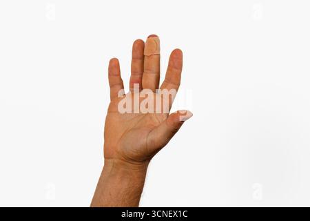 Une main est levée avec les doigts tendus, montrant un bandage sur un doigt. La main a un teint naturel et le fond est complètement blanc. Banque D'Images