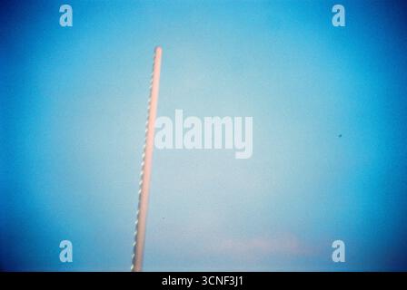 Barrière de stationnement surélevée avec une bande lumineuse contre un ciel bleu du soir, capturée sur film analogique avec une forte vignette et une ambiance cinématographique. Banque D'Images