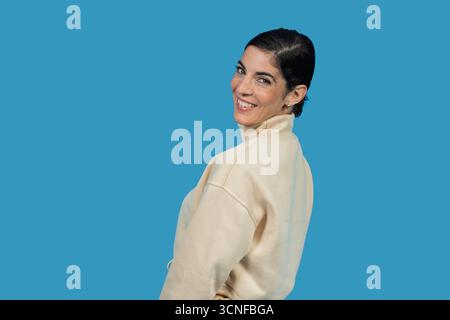 Femme dans un col roulé décontracté souriant et regardant par-dessus son épaule Banque D'Images