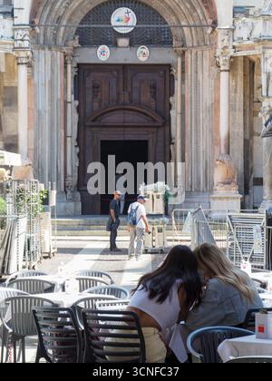 Cremona, Italie - 3 septembre 2025 entrée ensoleillée de jour d'été à l'église historique de Crémone en Italie avec des gens assis à des tables de café extérieures Banque D'Images
