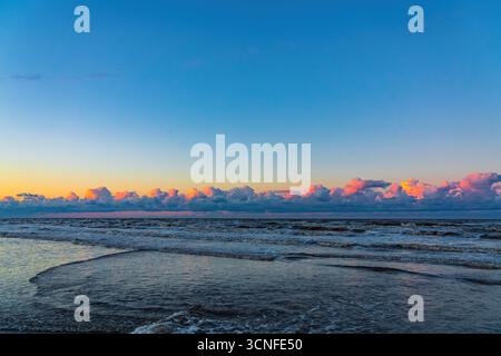 Beaux nuages colorés au-dessus de l'océan pendant le coucher du soleil Banque D'Images