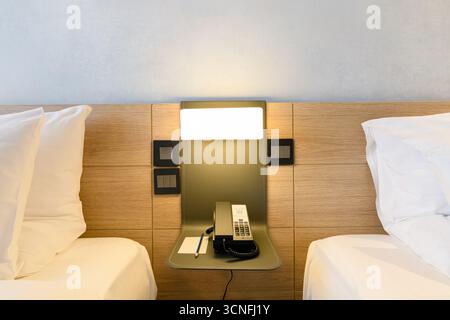 Le téléphone est sur la table dans la chambre, à côté du lit est un drap blanc et un oreiller. Banque D'Images