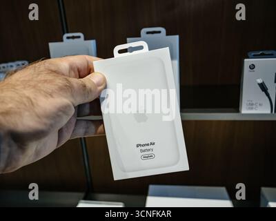 Paris, France - Sep 19, 2025 : une main tient la batterie Apple iPhone Air avec emballage MagSafe, exposée parmi d'autres accessoires sur les étagères à l'intérieur d'une Banque D'Images