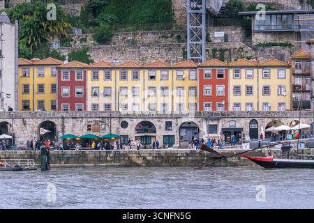 Maisons mitoyennes jaunes et rouges Row le long de Porto Riverfront Promenade. Quartier du front de mer de Cais da Ribeira, arcades en pierre, restauration en plein air, façades Banque D'Images