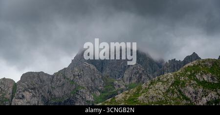 De sombres nuages orageux et de la brume enveloppent les sommets montagneux de granit dans les Lofoten, en Norvège. Banque D'Images