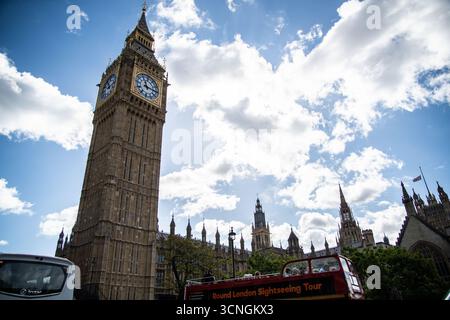 Vue sur le palais de Westminster et la tour Queen Elizabeth à Londres avec un bus à impériale rouge devant. Banque D'Images