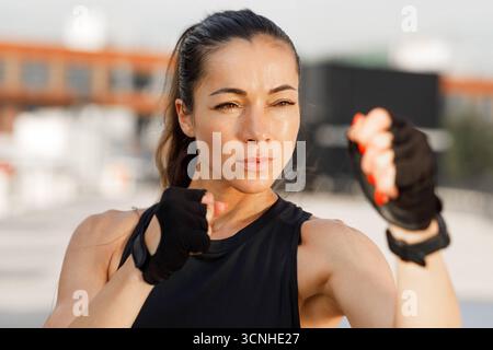 Portrait détaillé élevé d'une jeune femme debout dans une pose de combat, se préparant à la boxe d'ombre en plein air Portrait détaillé élevé d'une jeune femme stan Banque D'Images