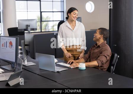 Diverses collègues féminines collaborant au bureau dans le bureau en utilisant un ordinateur portable et des graphiques, tasse à café Banque D'Images