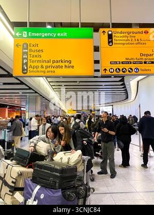 De grands panneaux d'information jaunes donnent des indications aux personnes arrivées au terminal 4 de l'aéroport de Londres Heathrow en Angleterre, au Royaume-Uni Banque D'Images