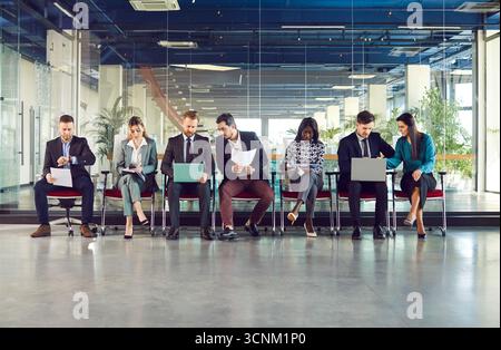 Groupe de diverses personnes intelligentes dans la rangée de chaises de hall de bureau moderne assis, travaillant avec des ordinateurs portables Banque D'Images